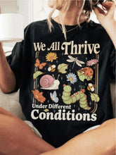 "We All Thrive Under Different Environments" slogan, colorful insect and floral print, regular-fit short-sleeved casual top.